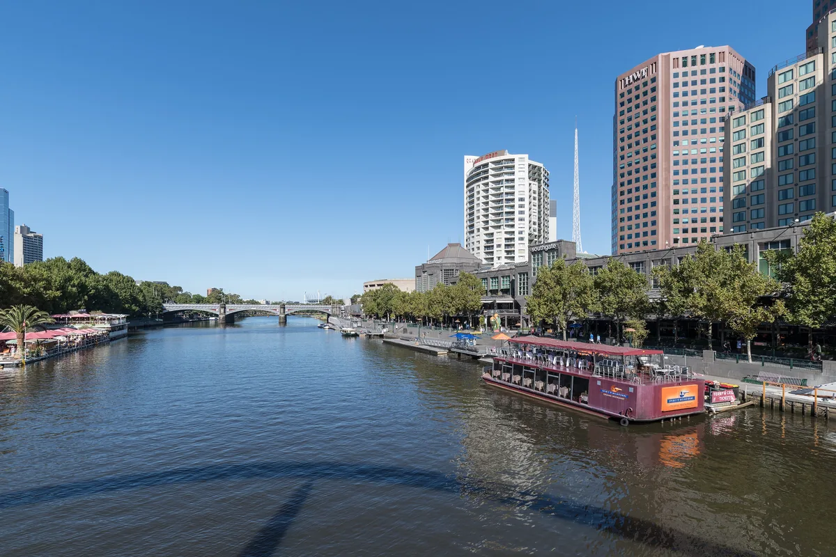 The Yarra on a clear day with a moored river boat at Southbank and towers rising along the bank.